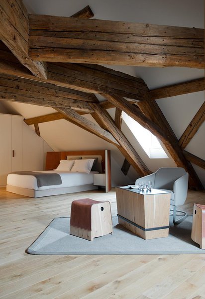 Simple et authentique, la chambre est aménagée avec des matériaux naturels : parquet en bois de chêne, tapis de laine et mobilier dessiné sur mesure. La tête de lit en cuir piqué façon sellier est surdimensionnée pour recouvrir une partie du mur.