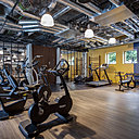 On retrouve les couleurs ocre et bleu emblématiques de la piscine Molitor jusque dans la salle de sport.