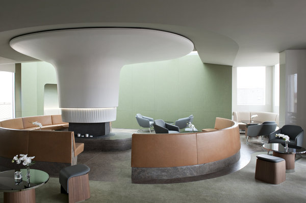 Autour de la cheminée centrale, posée comme une sculpture au centre de la salle, le sol en pierre se prolonge pour créer les dossiers des assises circulaires en cuir. La cheminée présente une alliance originale de matériaux, du staff pour la partie haute et une élégante armure faite de barrettes en porcelaine de forme géométrique recouvre le foyer.