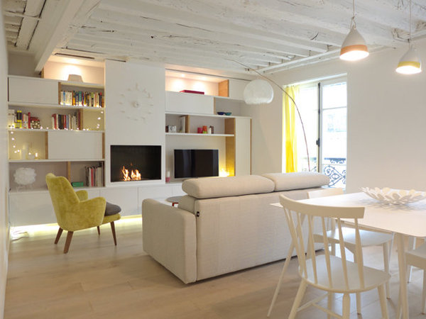 Après : La cheminée traditionnelle a été remplacée par un système de foyer urbain au bio-éthanol intégré. Et une grande bibliothèque conjuguant niches ouvertes et rangements fermés occupent toute la largeur de la pièce à vivre.