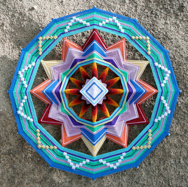 Coloris chatoyants et enroulements successifs du fil autour de bâtons, composent avec harmonie ce Mandala.