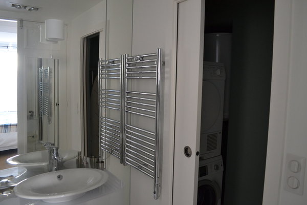 De la salle de bains, on accède à la buanderie cachée derrière une porte coulissante.