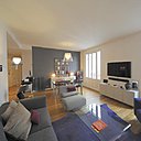 Dans la partie salon de la pièce, la couleur du canapé répond à celle du mur de la salle à manger.