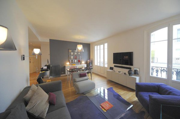 Dans la partie salon de la pièce, la couleur du canapé répond à celle du mur de la salle à manger.