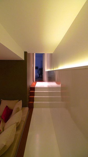 Le couloir est souligné par une bande peinte au sol de couleur rouge qui dessine un tapis graphique et sculpte les marches.