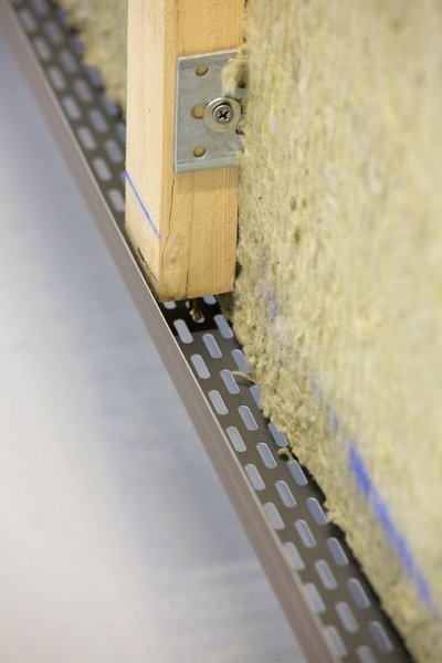 Étape 3 : Pose d'un pied de bardage perforé qui assure l'entrée de la lame d'air. L'alignement horizontal de ce pied garantit la bonne position de la première rangée de clins.