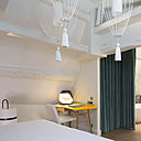 Sous les toits, la chambre Clara Gazul affirme un charme authentique avec un coin bureau et une douce séparation entre la chambre et la salle de bains. Rideau en velours de coton, Lelièvre. Suspension de Matteo Ugolini, Karman.