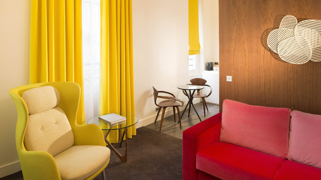 Dans la suite James Jewel, un petit salon attenant à la chambre. Guéridon de Out of Stock, Ligne Roset. Fauteuils Cherner conçus en 1958 par Norman Cherner. Applique de Philippe Nigro, Foscarini. Boiserie murale en noyer, Marotte. Canapé sur mesure, Peyroux&Thisy.