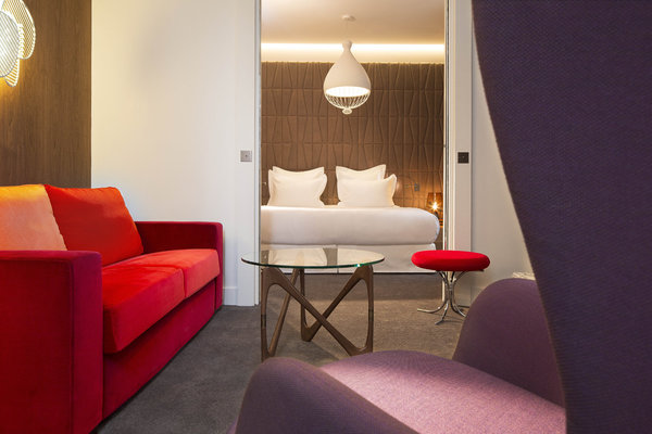 La suite Saint Léger. Tête de lit  en marqueterie de cuir, Studioart. Fauteuil de Jaime Hayon, Fritz Hansen. Canapé sur mesure, Peyroux&Thisy. Table basse, Objekto. Tabouret, Verner Panton, Verpan. Applique de Philippe Nigro, Foscarini. Suspension de Edmondo Testaguzza, Karman. Lampe de chevet de Magnus Pettersen, Italla. Moquette, Balsan.