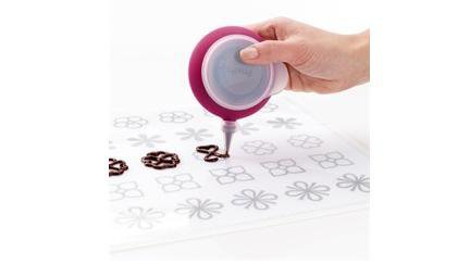 Pour réaliser des décorations en chocolat, ce tapis sert de patron. Il suffit de faire fondre le chocolat ou le caramel au micro-ondes, puis de reproduire la forme à l’aide du Décopen. En silicone. Kit composé d’un tapis transparent, de 4 patrons, d’une poche à douille Décopen et de 2 douilles. 33,99 €. Kit tapis de décoration. Lekué.