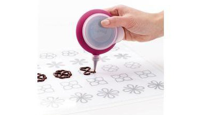 Pour réaliser des décorations en chocolat, ce tapis sert de patron. Il suffit de faire fondre le chocolat ou le caramel au micro-ondes, puis de reproduire la forme à l’aide du Décopen. En silicone. Kit composé d’un tapis transparent, de 4 patrons, d’une poche à douille Décopen et de 2 douilles. 33,99 €. Kit tapis de décoration. Lekué.