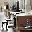 Exécuté de mains de maître par l’entreprise CAA, le bar oppose sa géométrie horizontale aux lignes verticales de la chapelle. Il est composé de modules solidaires (assises, panneaux amovibles, banquettes et strapontins) parés de poutres centenaires exhumées des réserves des Ateliers Perrault Frères.