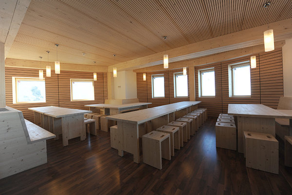 La salle commune, tout en bois, est chaleureuse. Elle reprend les codes du refuge traditionnel, la simplicité et la rusticité, les tables en bois, mais avec une touche évoquant le design scandinave.