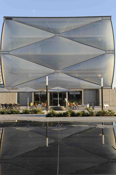 La façade est composée d’une membrane gonflable et transparente surdimensionnée. Son aspect capitonné très original est amplifié par un jeu de boîtes opaques, comme des boutons sur un coussin.