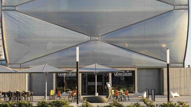 La façade est composée d’une membrane gonflable et transparente surdimensionnée. Son aspect capitonné très original est amplifié par un jeu de boîtes opaques, comme des boutons sur un coussin. La façade est composée d’une membrane gonflable et transparente surdimensionnée. Son aspect capitonné très original est amplifié par un jeu de boîtes opaques, comme des boutons sur un coussin.