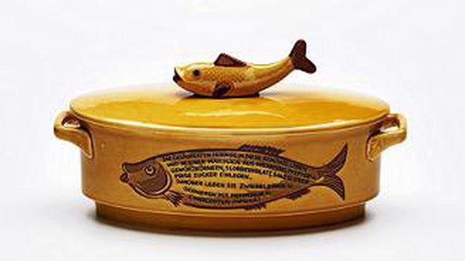 Haute en couleurs, cette terrine à harengs est l’œuvre de la faïencerie Staffel (Hesse, Allemagne). Réalisée en grès vernissé, elle date des années 1950 et « a été produite pour un usage professionnel (restaurants, brasseries) et une recette de harengs marinés a été inscrite sur son flanc en y reproduisant la forme du poisson. »