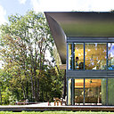 À l’extérieur, les façades en verre sont constituées d’un triple vitrage de 63 mm, avec gaz Argon et Krypton ; la terrasse en bois fait le lien entre la maison et la nature.