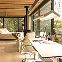 À l’étage, le cloisonnement partiel de l’espace nuit est conçu grâce à un système de rideaux qui isolent les différentes fonctions. La structure des panneaux de construction préfabriquée est  apparente. Poêle à bois (Speeta).