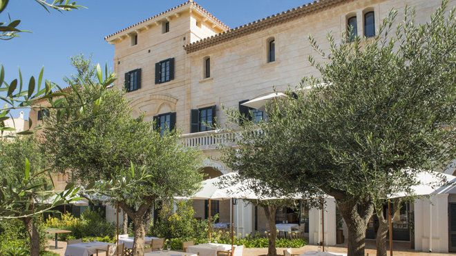 Le palais a été restauré laissant apparaître la belle pierre typique de l’île de Minorque. Le patio offre un cadre apaisant et ombragé avec ses oliviers et sa végétation abondante.