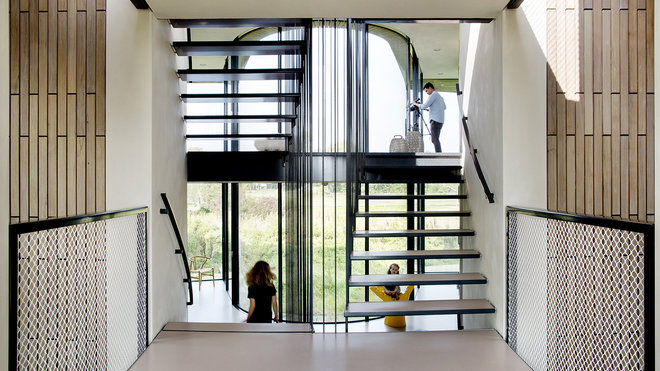 En pleine lumière, l’escalier central inséré dans un volume vitré en retrait, comme une colonne vertébrale, dessert les différents niveaux de la maison.