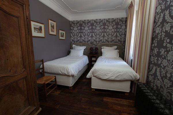 Papier-peint au décor damassé et rayures Directoire pour cette chambre modernisée par un pan de mur uni.