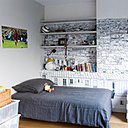 Hommage à Paris dans cette chambre d’adolescent qui offre un mur tapissé d’un papier-peint panoramique monochrome et graphique (modèle Vue de Paris Invalides Tour Eiffel, chez Ohmywall). La niche accueillant des étagères a été créée pour donner du volume à la pièce à la configuration très simple.