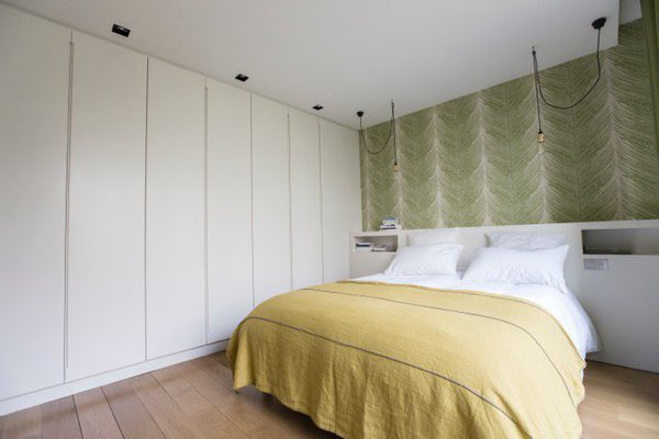 Un grand linéaire de placards occupe toute la longueur de la pièce. Ses portes laquées en blanc avec prise de main discrète s’intègrent dans l’espace.