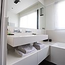 Le lavabo et son meuble horizontal ont été habillés de panneaux ultraminces de Kerlite qui offrent des dimensions de 1 à 3 mètres et permettent un façonnage sans joint visible. Appliques lumineuses, Mashiko 360 classic, chez Astro.