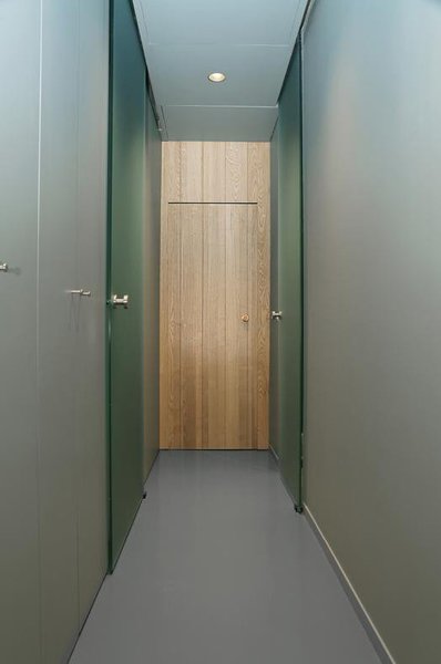 Dans le couloir qui mène aux chambres, à l’espace nuit et à la salle de bains, les portes en frêne et verre ont été retravaillées en continuité des murs pour conserver un caractère discret et apporter une certaine modernité.