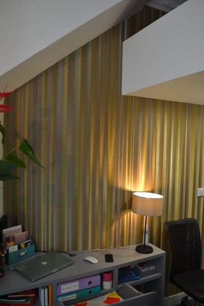 Les lignes du bureau en courbe suivent celles du mur habillé d’un papier à effet trompe-l’œil, imitant un effet de rideau dans une ambiance théâtrale.