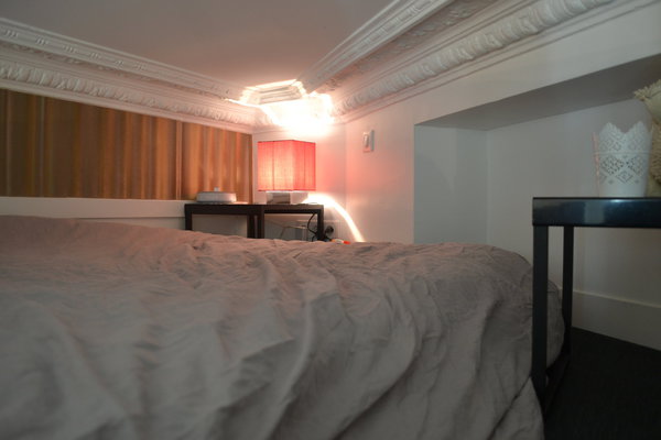 Le lit pour deux personnes est coiffé par les anciennes corniches et moulures conservées et restaurées du plafond.