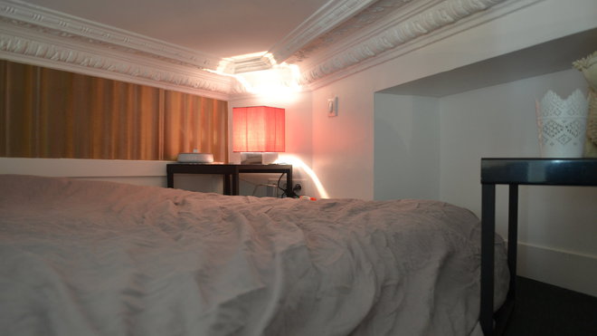 Le lit pour deux personnes est coiffé par les anciennes corniches et moulures conservées et restaurées du plafond.