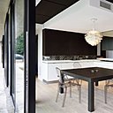 La cuisine est structurée par un faux plafond qui intègre l’aération thermique. Eléments de rangements, Boffi. En crédence, carrelage en grès cérame offrant une composition en patchwork de motifs de carreaux de ciment traditionnels, création Patricia Urquiola, pour Mutina. Fauteuils, modèle Louis Ghost, création Philippe Starck chez Kartell. Suspension PH en forme de pomme de pin, création Poul Henningsen éditée par Louis Poulsen.