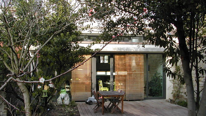 Extension réalisée sur une maison constituée d'un sous-sol semi enterré. Les espaces de vie du rez-de-chaussée sont agrandis et ouverts sur le jardin situé 1m40 en contrebas, à mi-niveau avec le sous-sol. La cuisine est réimplantée dans l’extension, de plain-pied avec le jardin et bénéficiant d’une vaste terrasse extérieure. La mise en place d’une large verrière et de grandes façades vitrées a également permis de faire pénétrer la lumière. Réalisation de l’agence d’architecture Philippe Bourillet.