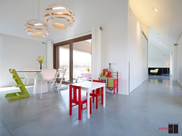 La salle à manger familiale offre un espace pour les enfants. La chaise de couleur vert anis s’adapte à la taille de l’enfant jusqu’à l’âge adulte et permet de l’accueillir à la table des grands (modèle Trip Trapp®, Knokke). Polybéton : Rapidsol bvba, Oeselgem. Plafonnage: DeMo Pleisterwerken, Moorslede.