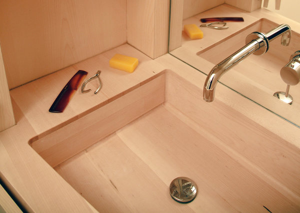 Relativement délicat pour un usage quotidien, l’espace lavabo et plan vasque a été entièrement dessiné et réalisé en sycomore massif. Elégance absolue pour cet espace toilette dissimulé dans un système de casier à la façon d’une cabine de bateau. Robinetterie Zazzeri.