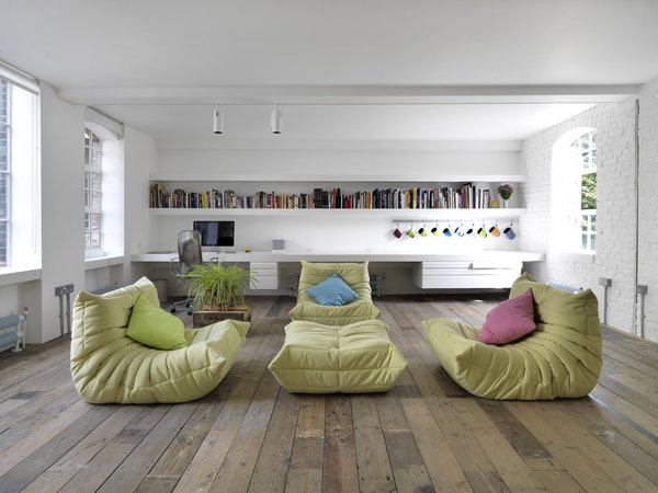 Sur un parquet en bois brut d’origine, l’espace est largement ouvert en lumière traversante. Fauteuils et pouf Togo dessinés par Michel Ducaroy en 1973 pour Ligne Roset.