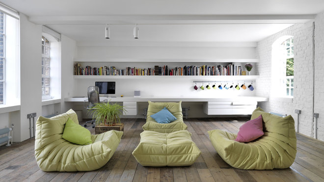 Sur un parquet en bois brut d’origine, l’espace est largement ouvert en lumière traversante. Fauteuils et pouf Togo dessinés par Michel Ducaroy en 1973 pour Ligne Roset.