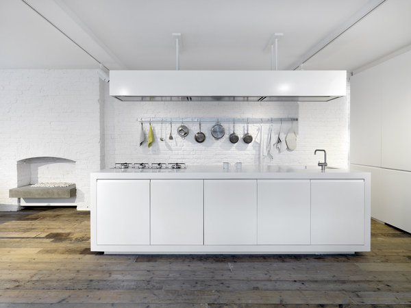 La cuisine high-tech dissimule tout le matériel dans des placards blancs immaculés. Le mur en briques d’origine est peint en blanc pour conserver l’authenticité de la matière.