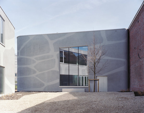 L’enduit extérieur du bâtiment au relief évoquant un agrandissement du faïençage du matériau céramique, est l’œuvre de l’artiste Jean Glibert.