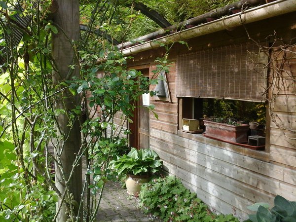 La roseraie en arceaux de bois de lamellé collé abritant la petite brocante de la Grenouillère.