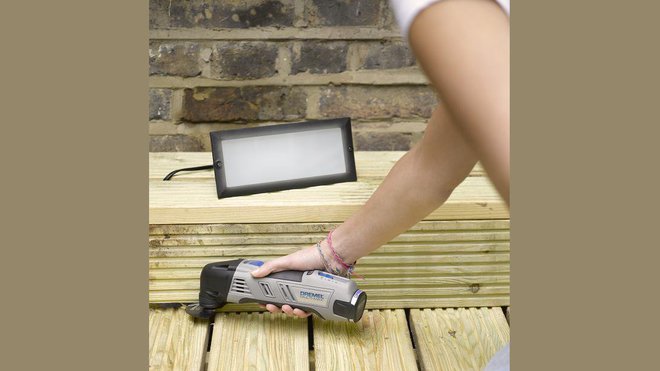 Etape 1 : mesurez la surface que vous souhaitez découper pour encastrer l’éclairage, en vous assurant que vous allez éviter tout matériel susceptible de se trouver derrière cette zone. Notez que tout bois traité sous pression (comme dans notre exemple) peut s’avérer plus difficile à couper. Notez également que la profondeur maximale de coupe facilement réalisable avec cette application est de 2 cm. Important : veillez à installer votre éclairage à une distance minimale de 1 mètre de toute source d’eau.