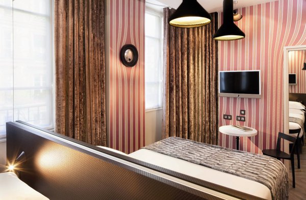 La chambre Dada, nous plonge dans un univers artistique un peu plus ancien. Les murs roses, ornés de jolis rideaux, suffisent à donner tout le cachet à  la pièce, dont les meubles restent sobres et simples.