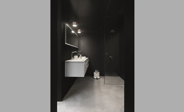 La salle de bains est fonctionnelle, avec une douche à l’italienne entièrement vitrée, et un meuble vasque surélevé pour plus de légèreté.