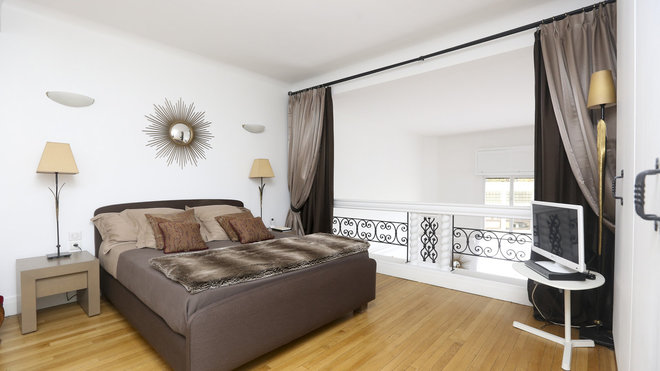 Sur la mezzanine, la chambre profite de la lumière diffusée par la baie vitrée pratiquée sur les deux niveaux de l’appartement.