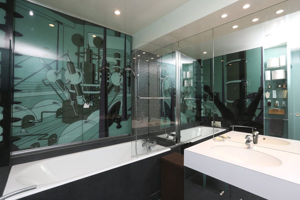 La salle de bains s’offre un œuvre murale résolument contemporaine.