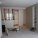 Phase travaux : le nouveau mur qui sépare le séjour de la chambre intègre des étagères de rangement. L’espace ouvert joue sur la transparence de la cuisine qui s’intègre parfaitement dans l’espace avec l’installation d’une large verrière dans l’esprit industriel.