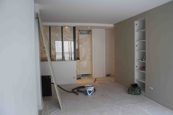 Phase travaux : le nouveau mur qui sépare le séjour de la chambre intègre des étagères de rangement. L’espace ouvert joue sur la transparence de la cuisine qui s’intègre parfaitement dans l’espace avec l’installation d’une large verrière dans l’esprit industriel.