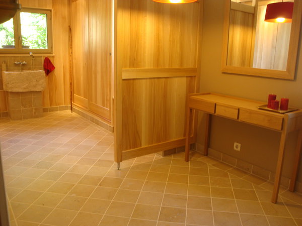 En décoration, l’utilisation de la pierre naturelle et du bois offre une combinaison harmonieuse de matériaux chaleureux et écologiques. Au sol, un dallage en Pierre de Bourgogne, finition adoucie.