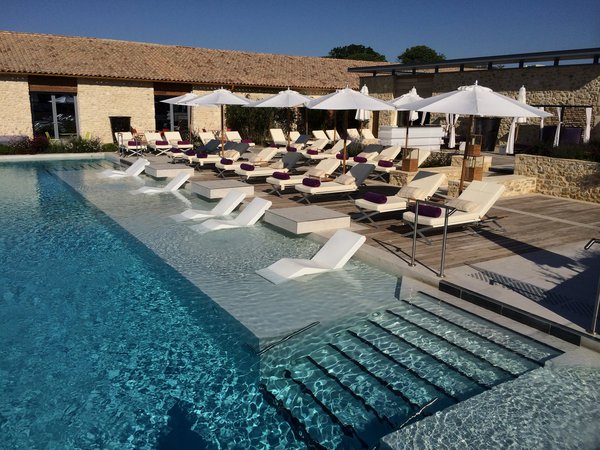 La modernité de la piscine et du mobilier outdoor contraste avec le caractère ancien de la bâtisse et son toit de tuiles de terre cuite aux teintes nuancées.